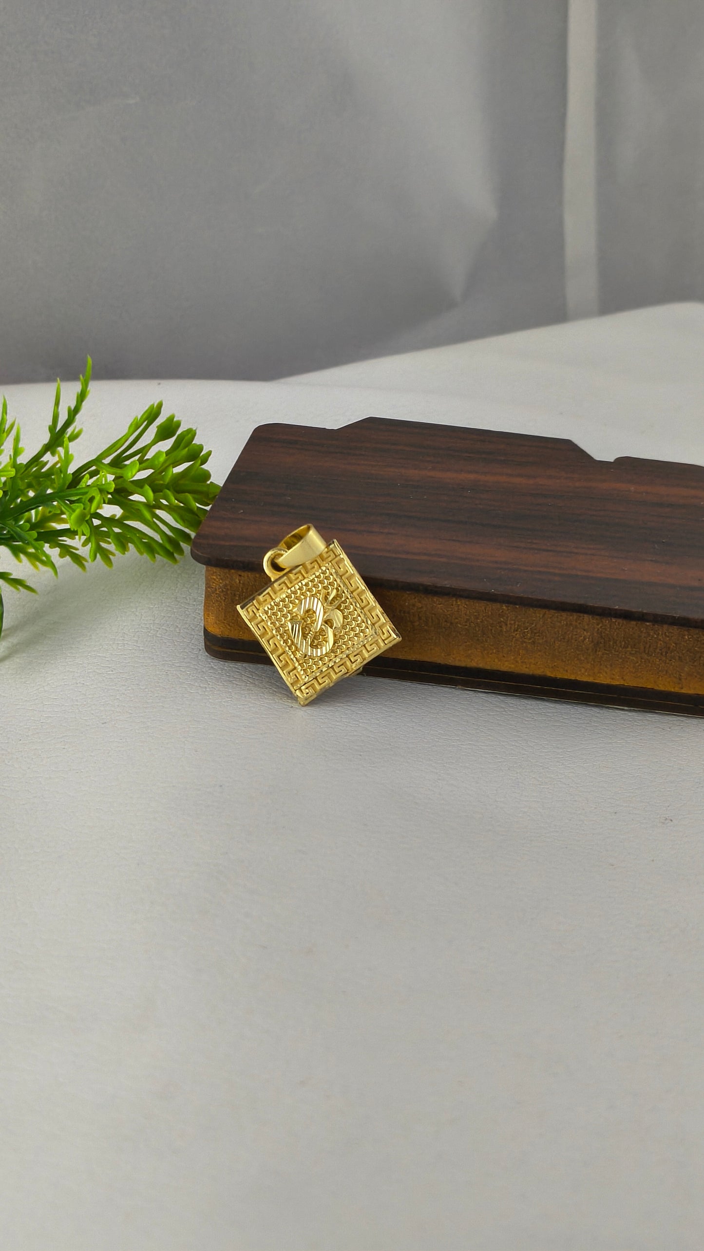 square-shaped gold-plated Om pendant.